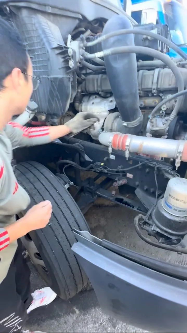 A person checking a truck engine bay